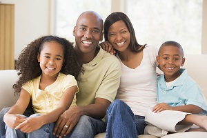 family smiling at the camera sitting on a couch